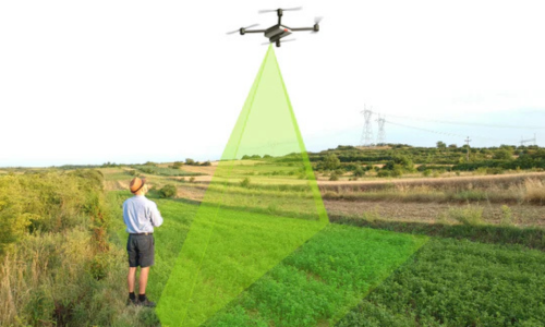 A man standing in a field flying a drone with a graphic indicating it's range.